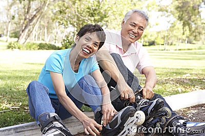 Senior Couple Putting On In Line Skates In Park Stock Photo