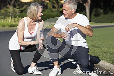 Senior Couple Resting And Drinking Water After Exercise Stock Photo