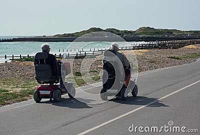 Senior couple ride together on mobility scooters. Editorial Stock Photo