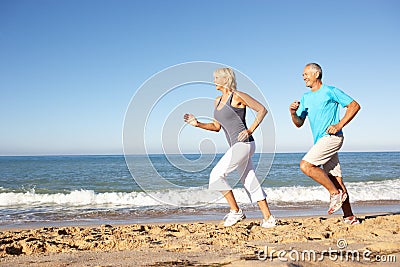 Senior Couple Running Along Beach Stock Photo