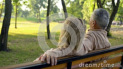 Senior couple sitting on bench, enjoying countryside weekend together, travel Stock Photo