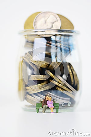 Senior couple sitting in front of a jar full of money with pension savings Stock Photo