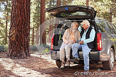 Senior couple sitting in open car trunk preparing for a hike Stock Photo