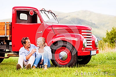 Senior couple sitting at the red vintage car Stock Photo