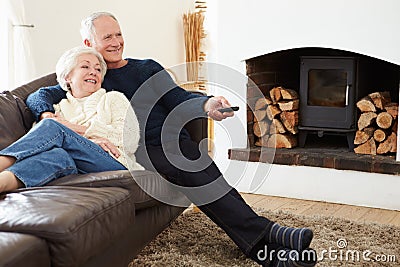 Senior Couple Sitting On Sofa Watching TV Stock Photo