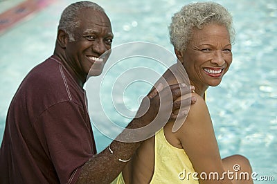 Senior Couple sitting by swimming pool portrait. Stock Photo