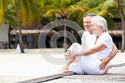 Senior Couple Sitting On Wooden Jetty Stock Photo