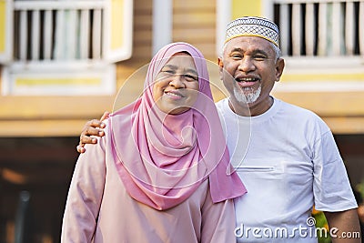 Senior couple standing in front of wooden house Stock Photo