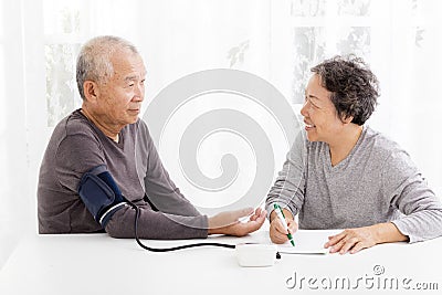 Senior couple taking blood pressure in living room Stock Photo