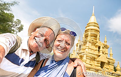 Senior couple taking selfie at golden temple in Ko Samui - Happy retired people traveling to Thailand wonders - Active elderly Stock Photo