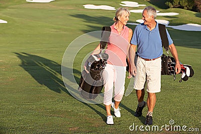 Senior Couple Walking Along Golf Course Stock Photo