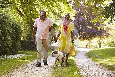 Senior Couple Walking With Pet Bulldog In Countryside Stock Photo