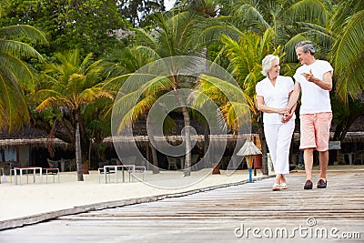 Senior Couple Walking On Wooden Jetty Stock Photo