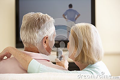 Senior Couple Watching Widescreen TV At Home Stock Photo