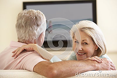 Senior Couple Watching Widescreen TV At Home Stock Photo