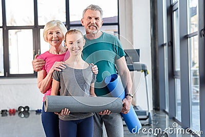 Senior couple with yoga mats and smiling girl standing together in fitness class Stock Photo