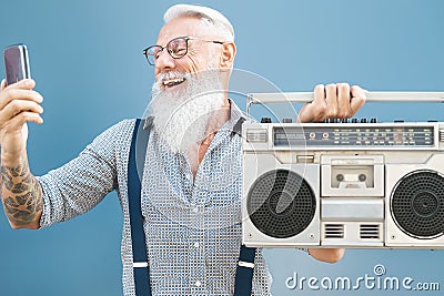 Senior crazy man using phone while listening music with vintage boombox - Hipster guy having fun using mobile smartphone Stock Photo