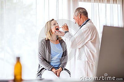 Senior doctor examining a young woman in office. Stock Photo