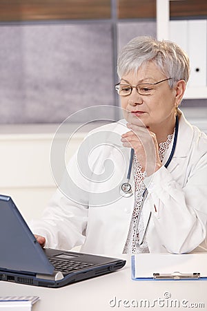 Senior doctor looking at computer Stock Photo