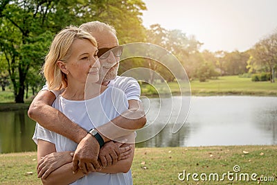 A senior elderly couple cuddle in a park in summer time Stock Photo