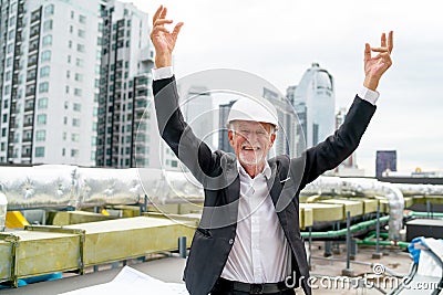 Senior engineer raises two hands with smiling also look at camera to express happiness from successful of project and he stay on Stock Photo