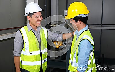 Senior engineer touch the shoulder of junior engineer. They feeling happy and fun on finishing work Stock Photo