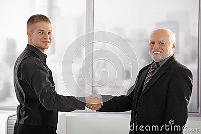 Senior executive shaking hands with young employee Stock Photo