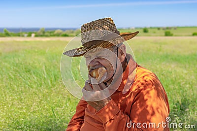 Senior farmer eating handmade patty under tree shadow near his field Stock Photo