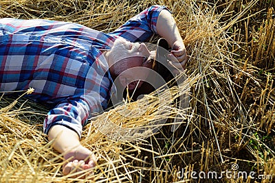 Senior farmer in the hay. Senior taking a break and relaxing on a hay on an summer day. Grandfather laying on haystack Stock Photo