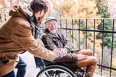 Senior father in wheelchair and young son on a walk. Stock Photo