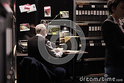 Senior federal agent sitting at desk table in arhive room Stock Photo