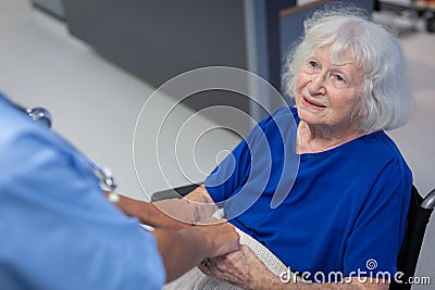 Senior female patient holding hands of surgeon in hospital corridor Stock Photo