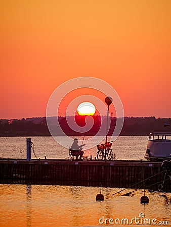 Senior fisherman fishing at dawn on a pier, real candid people Stock Photo