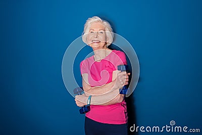 Senior fitness woman training with dumbbells isolated on blue Stock Photo