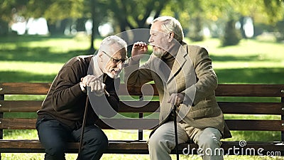 Senior gentlemen talking to his hearing impairment old friend, health problems Stock Photo