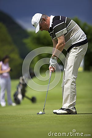 Senior golf player putting at hole. Stock Photo