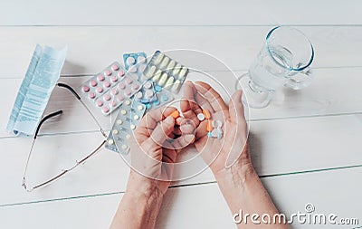 Senior hands with pills and drugs on table, glass of water. Stock Photo