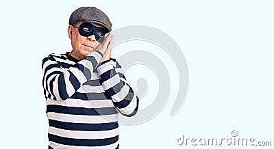 Senior handsome man wearing burglar mask and t-shirt sleeping tired dreaming and posing with hands together while smiling with Stock Photo