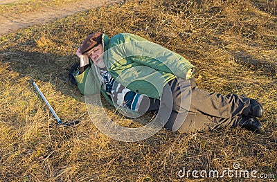 Senior hiker has short rest lying on the roadside at autumnal evening Stock Photo