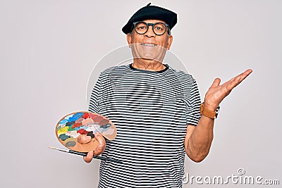 Senior hoary artist man wearing french beret drawing using paintbrush and palette with colors very happy and excited, winner Stock Photo