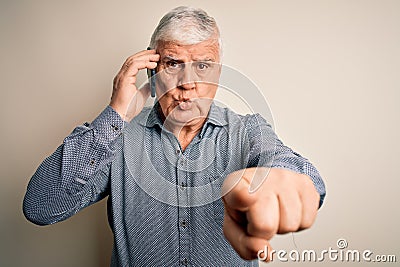 Senior hoary man having conversation talking on the smartphone over white background pointing with finger to the camera and to Stock Photo