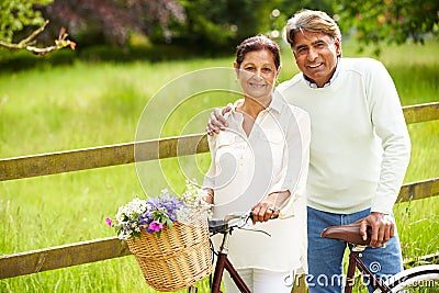 Senior Indian Couple On Cycle Ride In Countryside Stock Photo