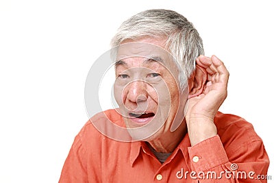 Senior Japanese man with hand behind ear listening closely Stock Photo