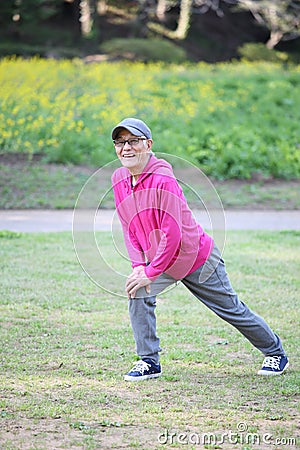 Senior Japanese man wearing pink parka doing calf stretch Stock Photo