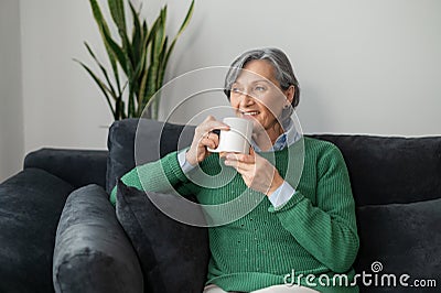 Senior lady daydreaming and enjoying a hot drink Stock Photo