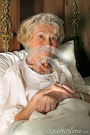 Senior lady in her nightgown in bed Stock Photo