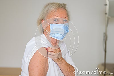Senior lady lifting her sleeve to prove she has no ill effects from the Covid-19 vaccine Stock Photo