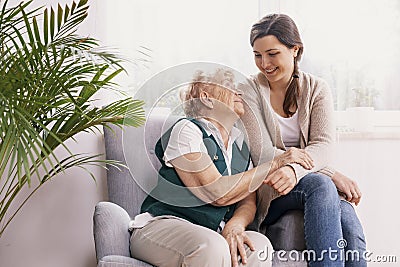 Senior lady sitting in armchair at nursing home, supporting nurse Stock Photo