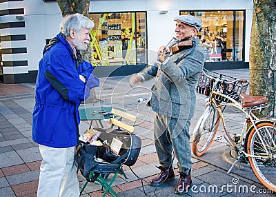 Senior male chats with street musician Editorial Stock Photo