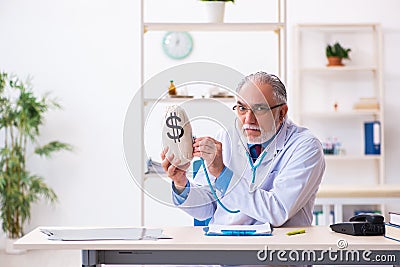 Old male doctor holding moneybag in the hospital Stock Photo